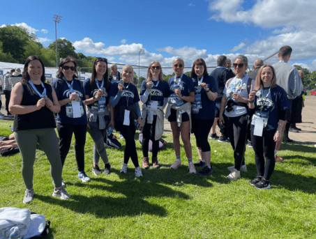 A group of women wearing ASCERT T-shirts and holding medals.