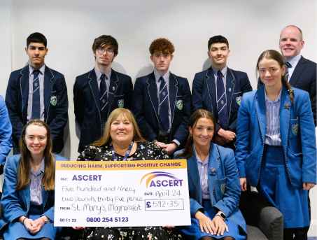 Fiona from ASCERT sits with a cheque alongside a group of students and their teacher from St Mary's Grammar School, Magherafelt. The school raised £592.35 for ASCERT.