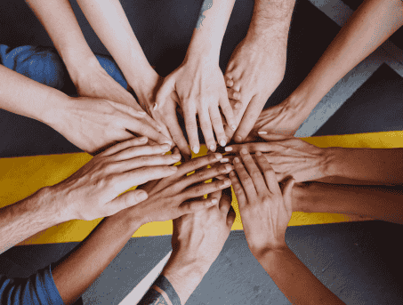 Multiple sets of hands on top of each other in a circle.